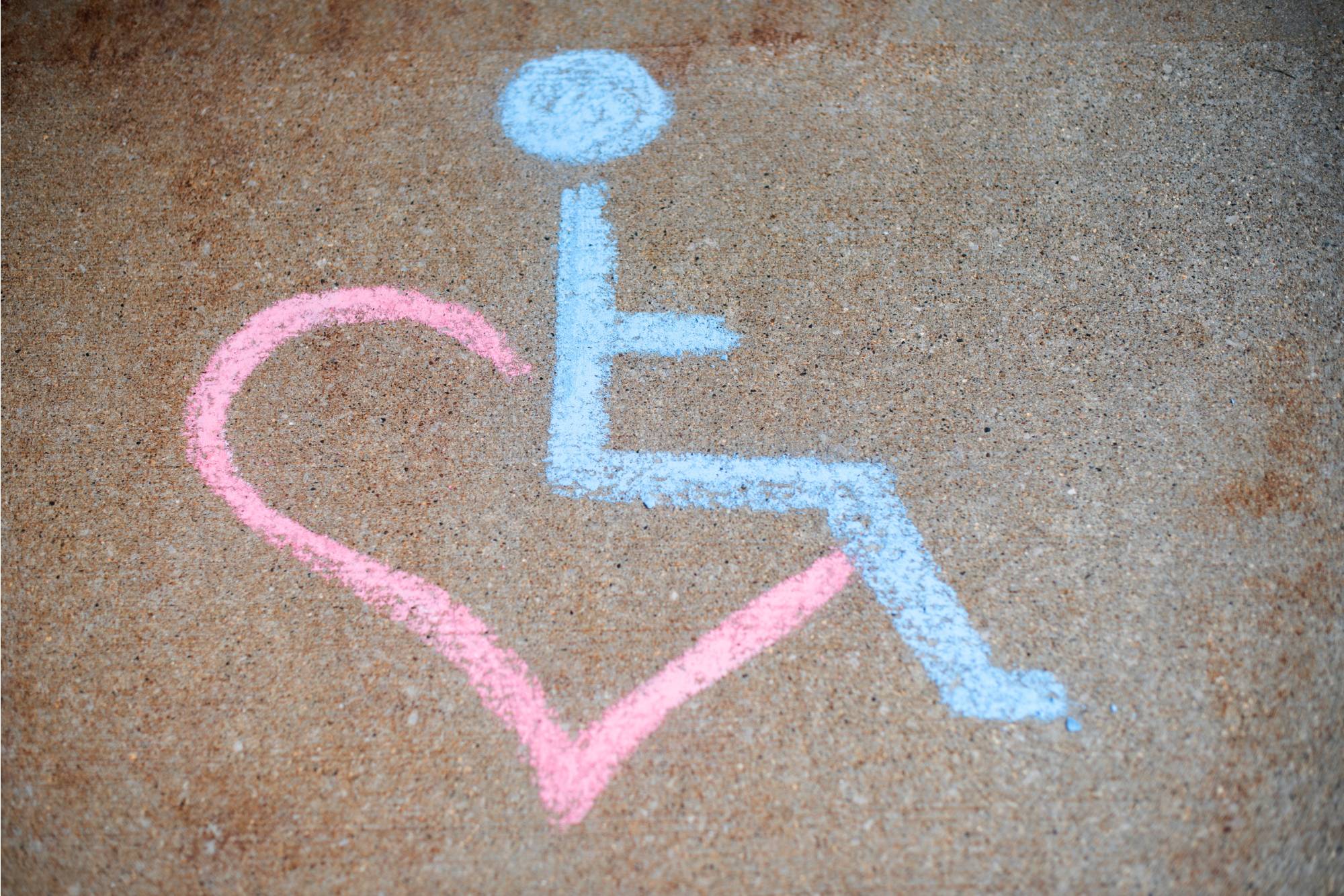 Chalk drawing of handicapped symbol with a heart integrated into the bottom left